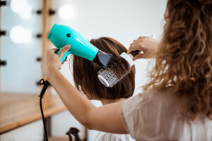 Female hairdresser making hairstyle to brunette girl in beauty salon.